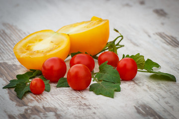Yellow tomato and cherry tomatoes with green leaves in garden on sunny day