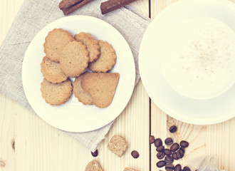 Ginger biscuits, cinnamon, a cup of hot coffee. Walnuts, hazelnuts on a wooden background. Tonned photo