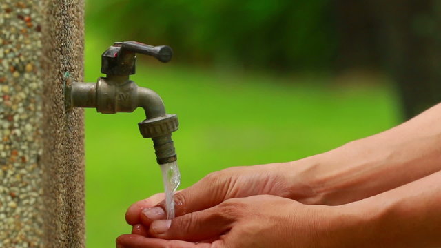 Man hand washing with tap water in the park.