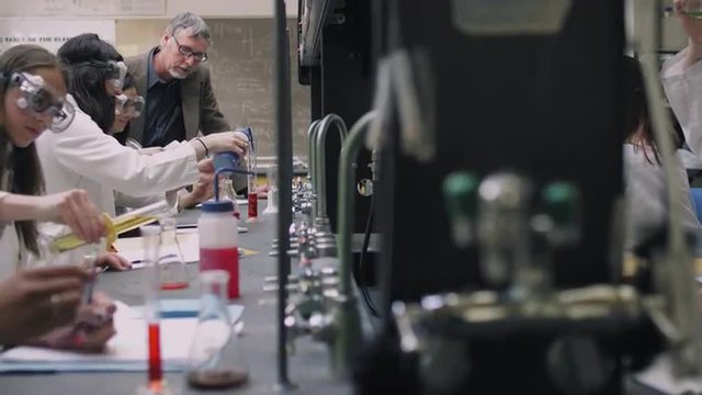 A professor helps his students with their science experiments