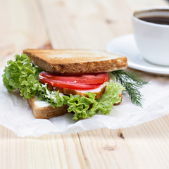 Sandwich and cup of black coffee on the table