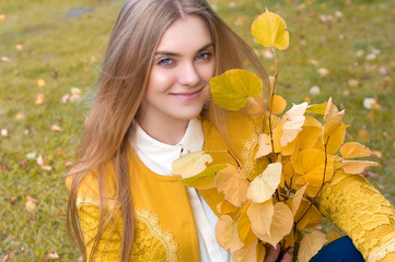 Naklejka premium Young blond woman with yellow leaves in park