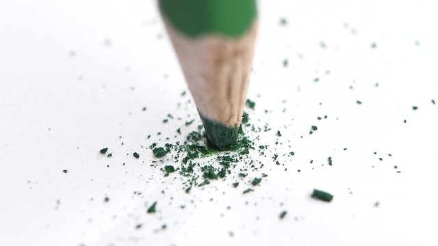 Broken head of sharp green pencil on a white, slow motion