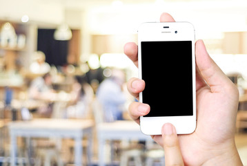 Hand holding smart phone over blur restaurant background