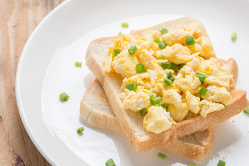 Scrambled eggs on toast, garnished with onion.