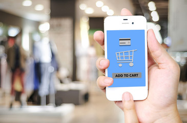 Hand holding smart phone with add to cart words on screen over b