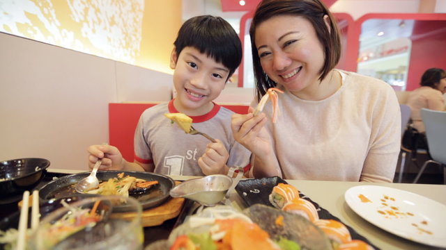 Happy asian family eating sushi in a restaurant with smile face
