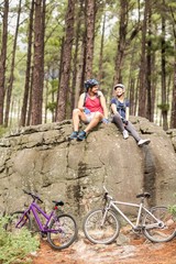 Young happy biker couple sitting on a rock