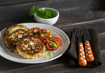 delicious vegetarian cabbage cutlets and fresh tomatoes on a light plate  on a dark wooden surface