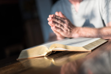Man praying hands on a Bible