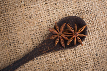 Star anise in a wooden spoon on sacking