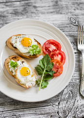 toast with soft cheese and quail eggs on a white plate on a light wooden background