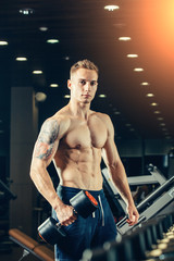 Fototapeta na wymiar Male athlete with a dumbbell in the gym lean on row