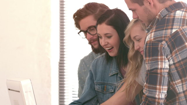 Laughing hipster team watching a pc monitor