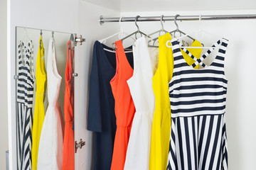 a series of bright modern fashion women's dresses on hangers in