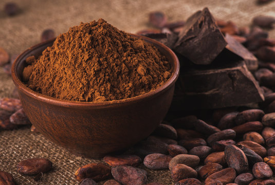 cocoa powder in a brown ceramic bowl, raw cocoa beans in the pee
