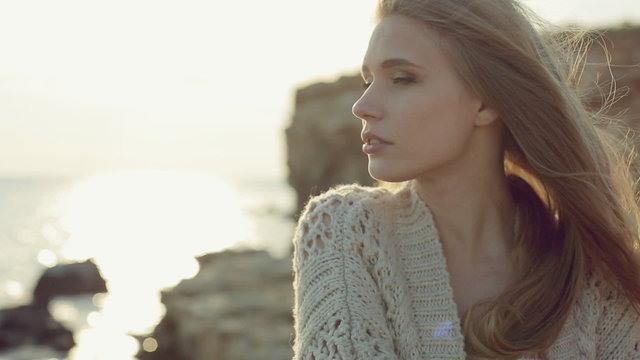 Sensual green-eyed blonde wearing a knitted jacket standing near