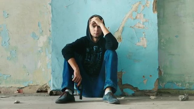 Young man sitting in an abandoned house. The concept of