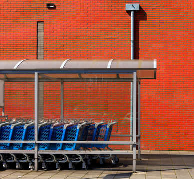 Supermarket front with row of blue shopping carts and red brick wall