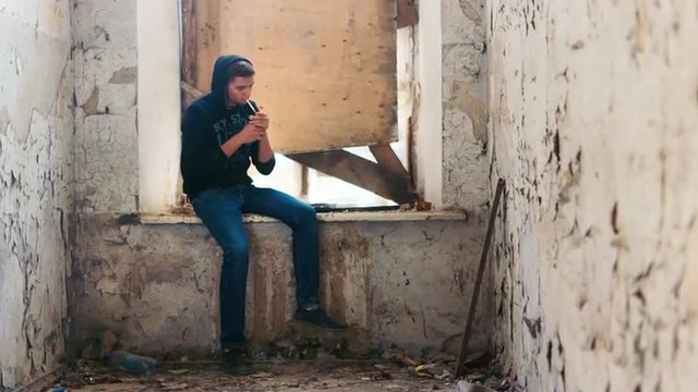 The young man smokes in an abandoned house. The concept of