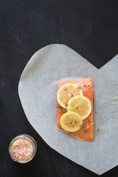 Salmon with lemon slices, thyme, pepper and Himalayan salt to bake in parchment