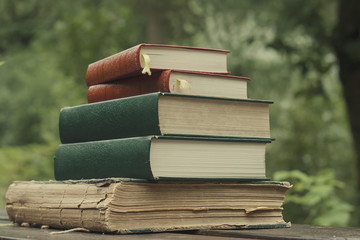 pile of five old books in a garden wooden table