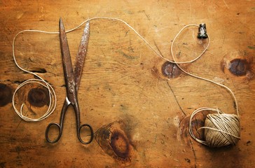 Old wood table with thimble, thread and scissor makes a frame for text in rustic vintage style. Top...