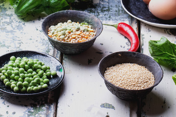 Quinoa Burger ingredients: quinoa, mangold, dry grain mix, chili pepper, eggs green peas basil on white rustic board