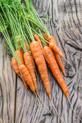 Carrots with greens on the old wooden table.