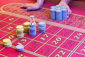 Casino American Roulette gambling table with a playing chips on the layout. Croupier is doing payout.