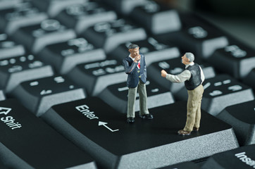 miniature people shake hand on keyboard backgroud