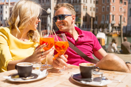 Young cheerful couple drinking Aperol Spritz cocktail in cafe