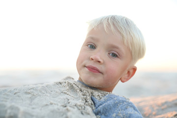 Zabawa w piasku na plaży.Wesoły chłopiec bawi się w piasku na plaży - obrazy, fototapety, plakaty