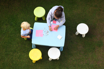 Dzieci bawią się w ogrodzie, rysują kredkami