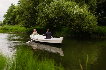 Fototapeta na wymiar жених и невеста в белой лодке на озере