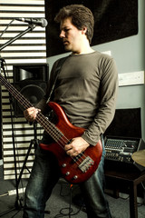 Obraz premium Rock singer playing bass in the rehearsal Studio