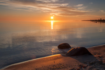 Sunrise over the sea horizon. The calm Baltic Sea is colored in blue, orange and yellow. The island of Gotland, Sweden.