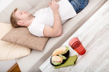 Obraz na płótnie Canvas Young man with a Sandwich on the Sofa 