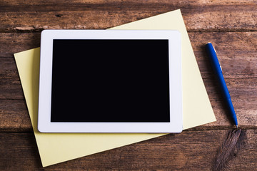 Blank modern digital tablet with papers and pen on a wooden desk. Top view. High quality detailed...