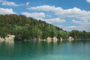 Fototapeta premium Lake with green water and hill with trees