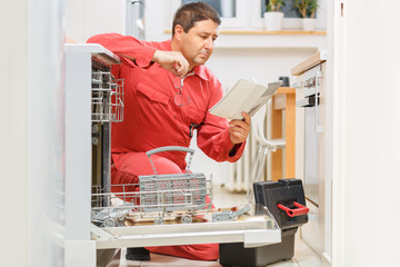 Handy man reading the instruction manual of the dishwasher in the kitchen