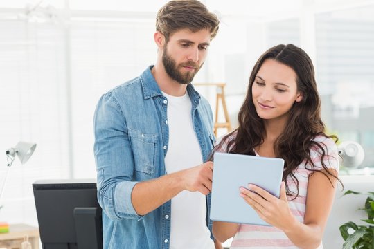Casual business partners holding tablet 