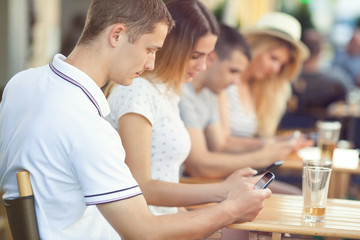 Group of teenagers sitting in a cafe spanding time with (virtual) friends