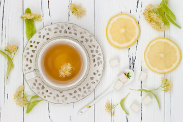 Cup of herbal tea with linden flowers on a old wooden background. Top view