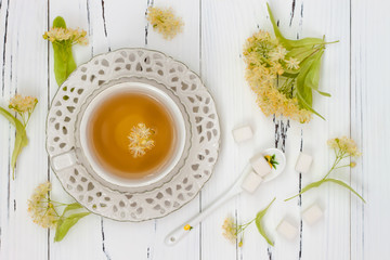 Cup of herbal tea with linden flowers on a old wooden background. Top view