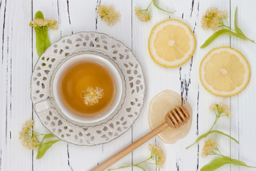 Cup of herbal tea with linden flowers, lemon and honey on a old wooden background. Top view