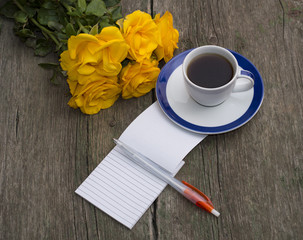 yellow roses, coffee and the handle with a notebook on a shabby