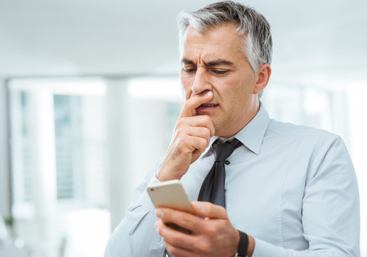 Confused Businessman Using A Smart Phone