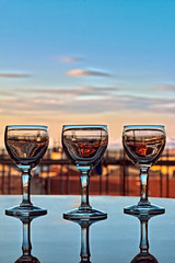 three liqueur glasses reflected on the table at sunset 