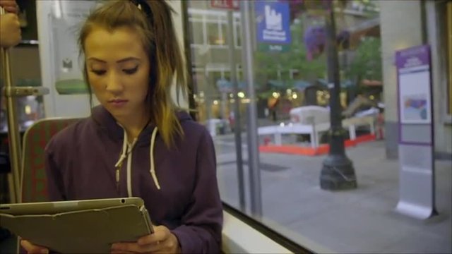 Cute asian girl uses her tablet computer on the train